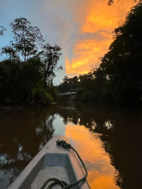 Atardecer anaranjado visto desde una canoa en el río