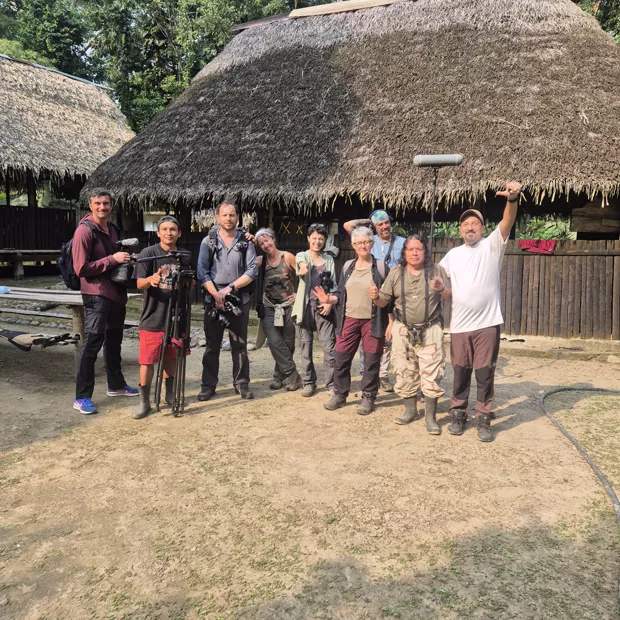 Miembros de la comunidad waorani frente a una casa de techo de paja