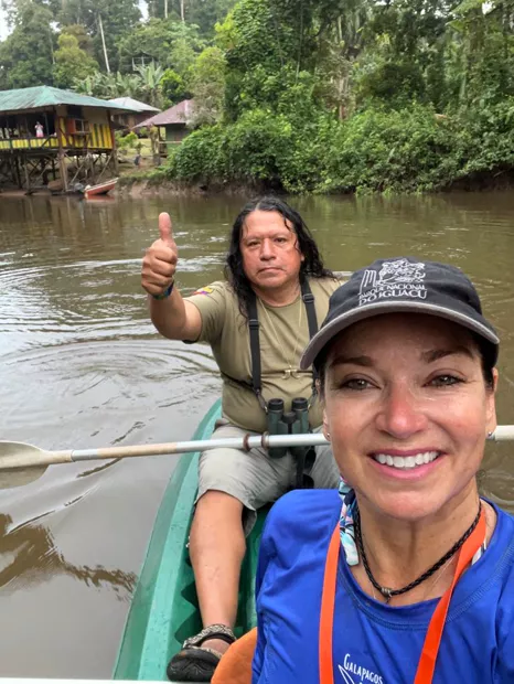 Guía y viajera remando y sonriendo en una canoa