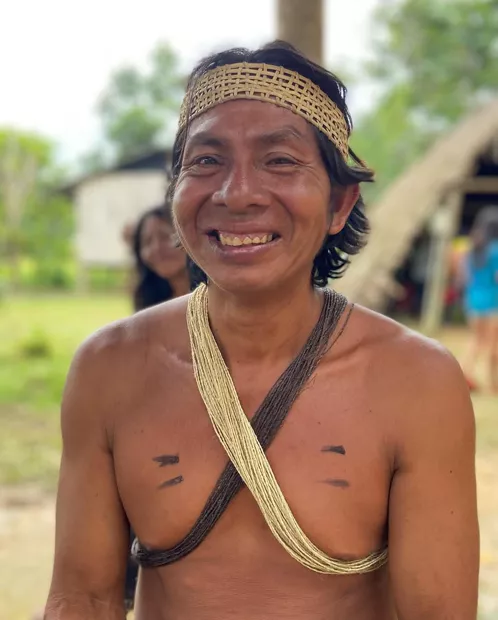 Retrato de un hombre waorani sonriente con corona tejida